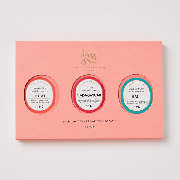 Pink chocolate bar collection packaging with three circular labels on a light gray background