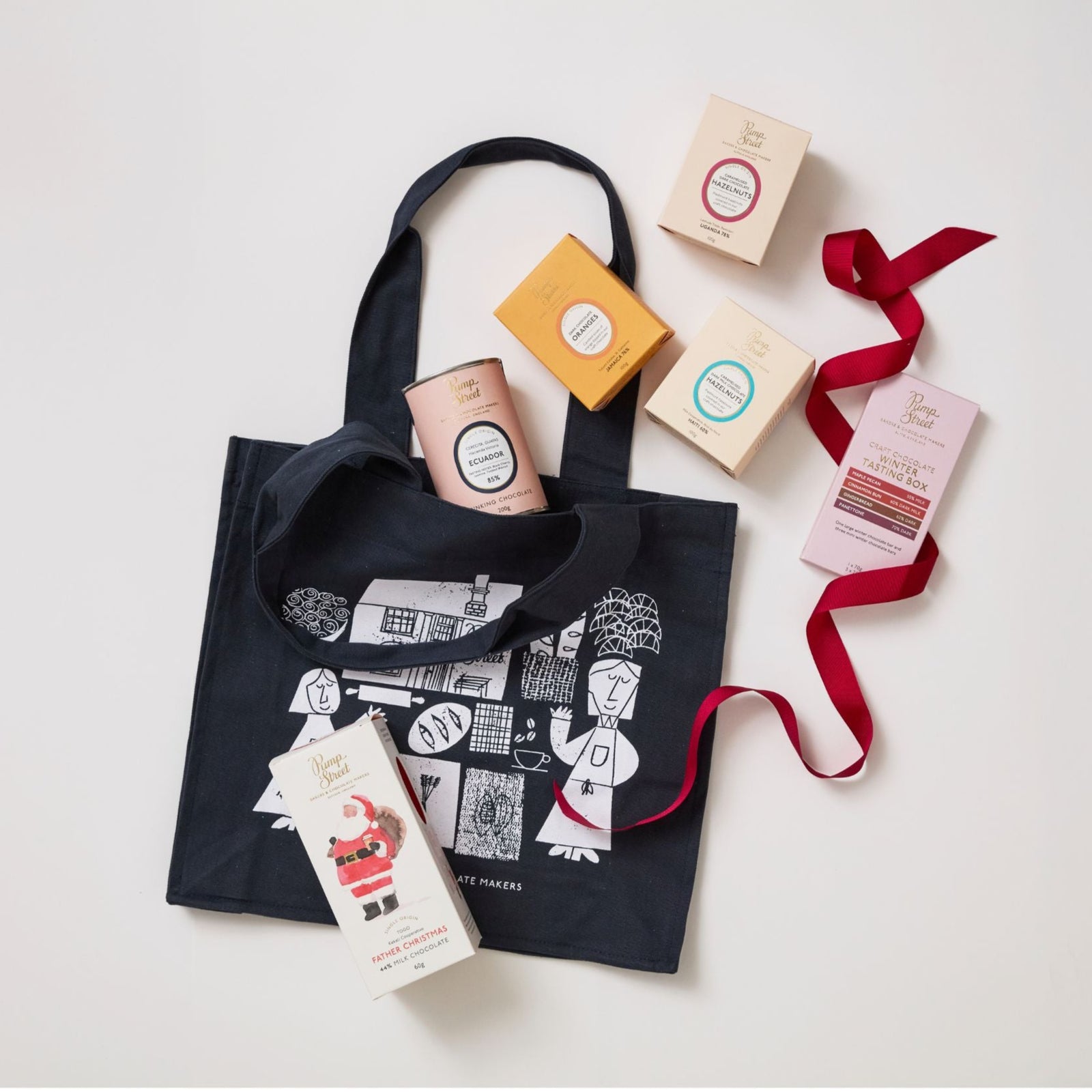 Black tote bag with printed designs, small boxes, and a red ribbon on a white background